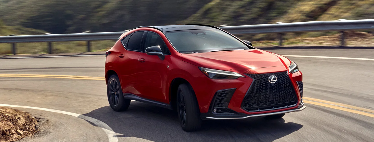 Front side view of a red 2026 Lexus NX making a turn on a road