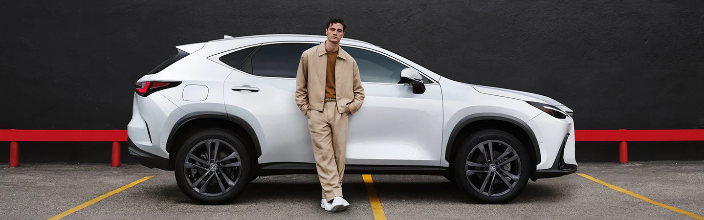 Man leaning on a white parked 2026 Lexus NX in a parking lot