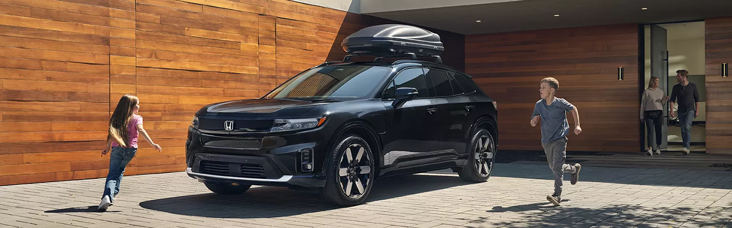 Children running around a 2026 Honda Prologue parked in front of a house