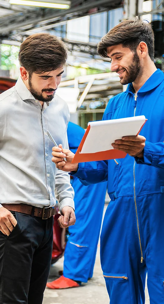 two people discussing service on vehicle in service bay behind them