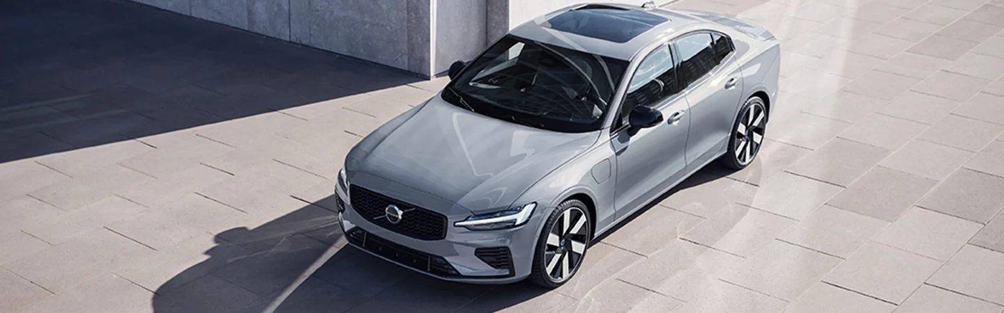 Front side view of a parked gray 2025 Volvo S60 in font of a building