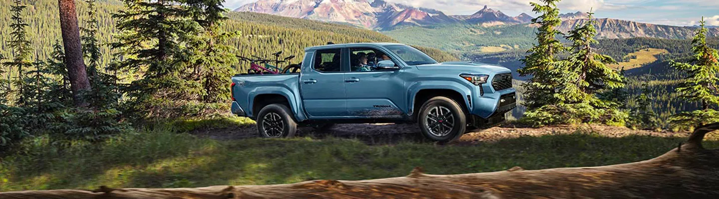 2026 Toyota Tacoma parked in front of mountains with trees around it