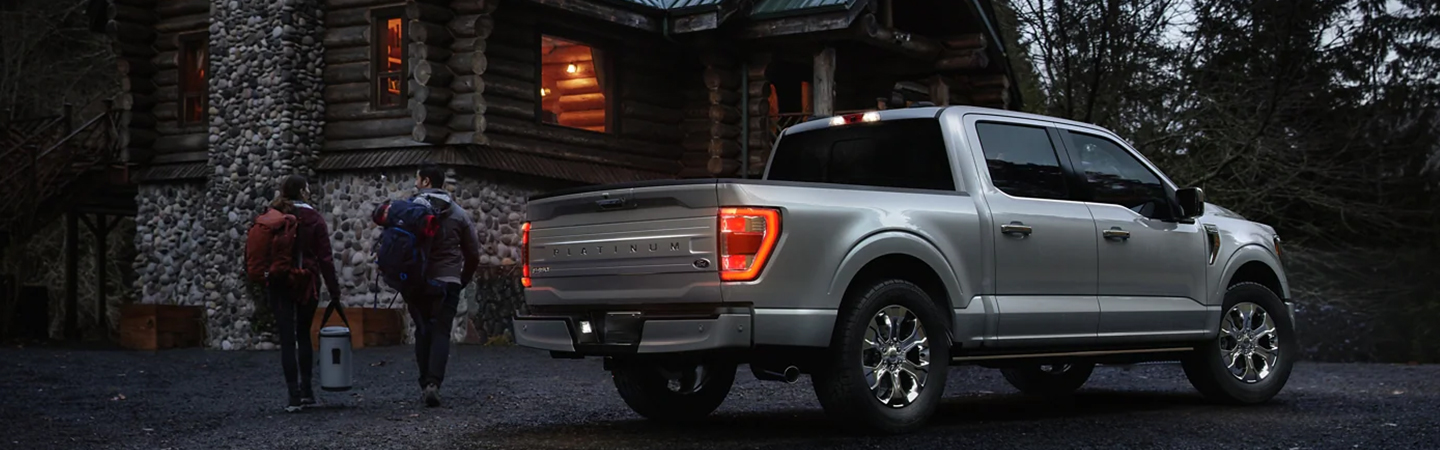 2023 Ford F-150 parked at night by a house with man and woman walking to the front door