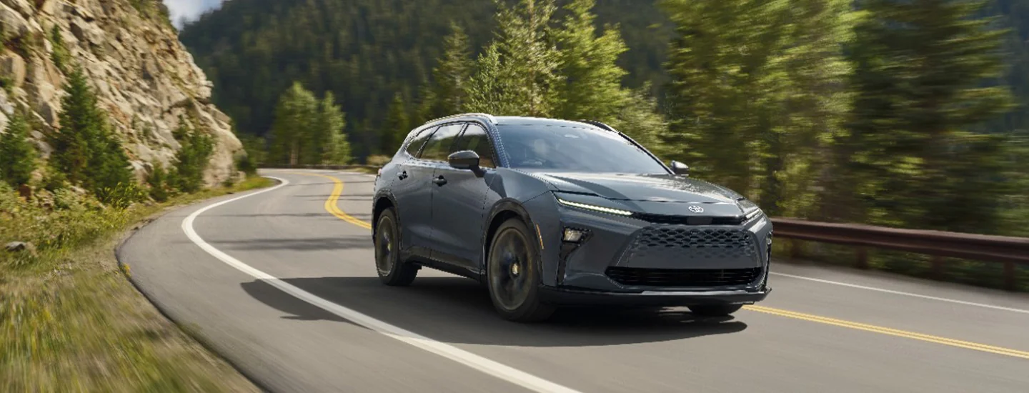 Front view of a 2025 Toyota Crown driving on a road in the forest