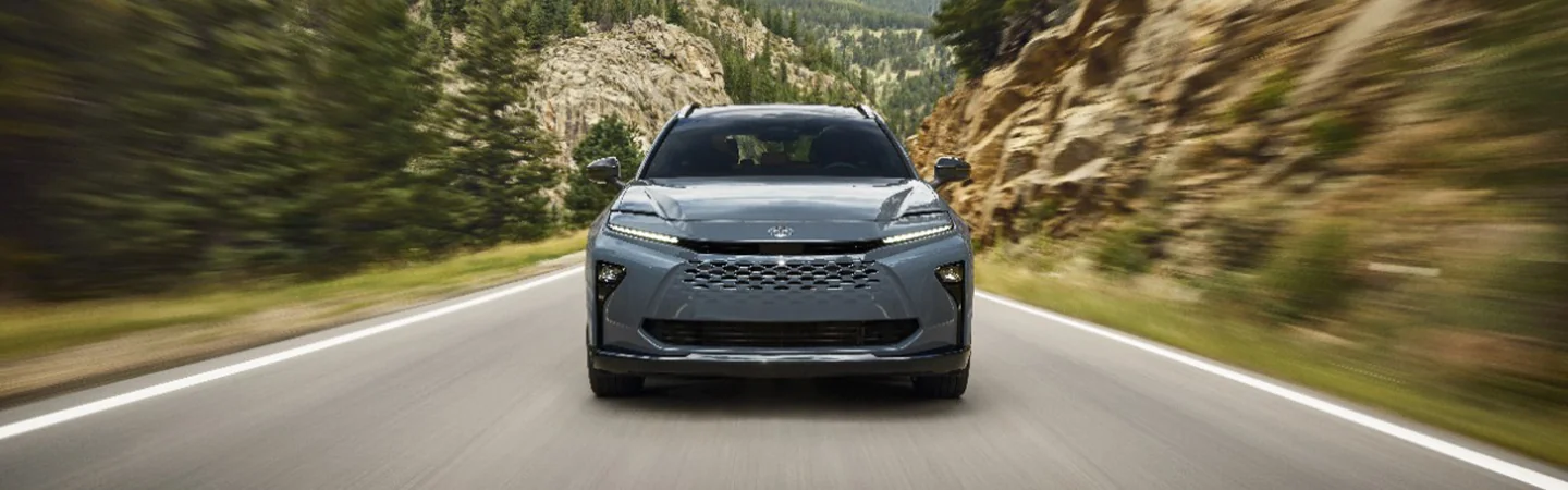 front view of a 2025 Toyota Crown driving on a road though a forest