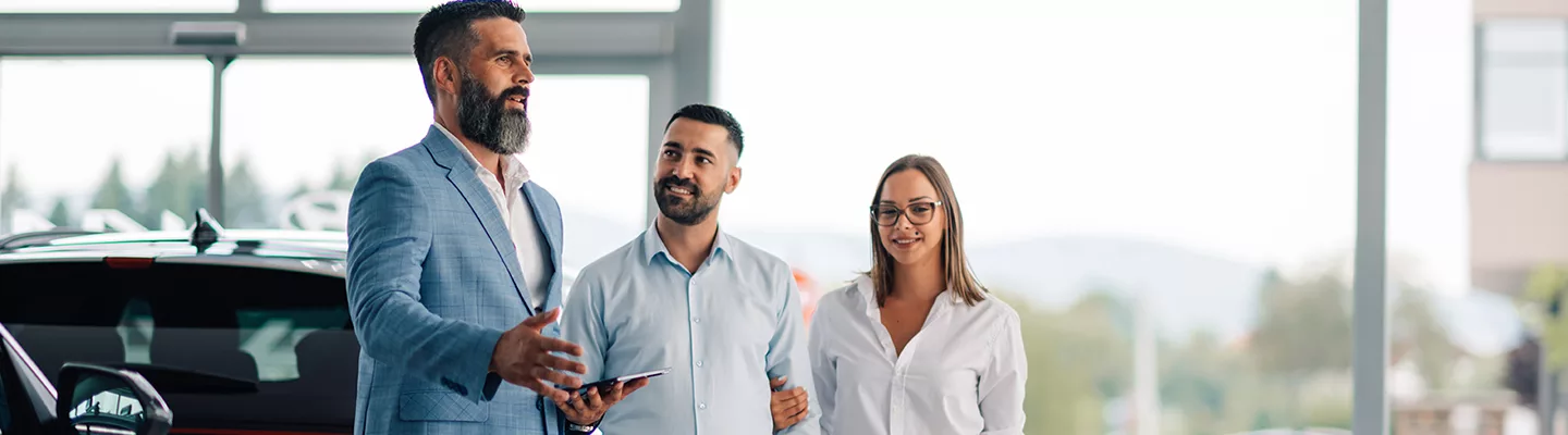 salesman talking with a husband and wife in the dealership