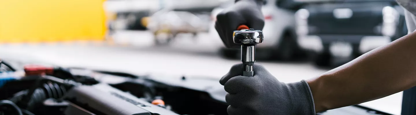 Mechanic using tools under the hood of a car