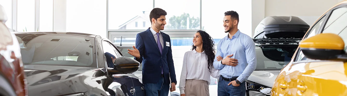 Couple discussing car purchase with salesperson in dealership