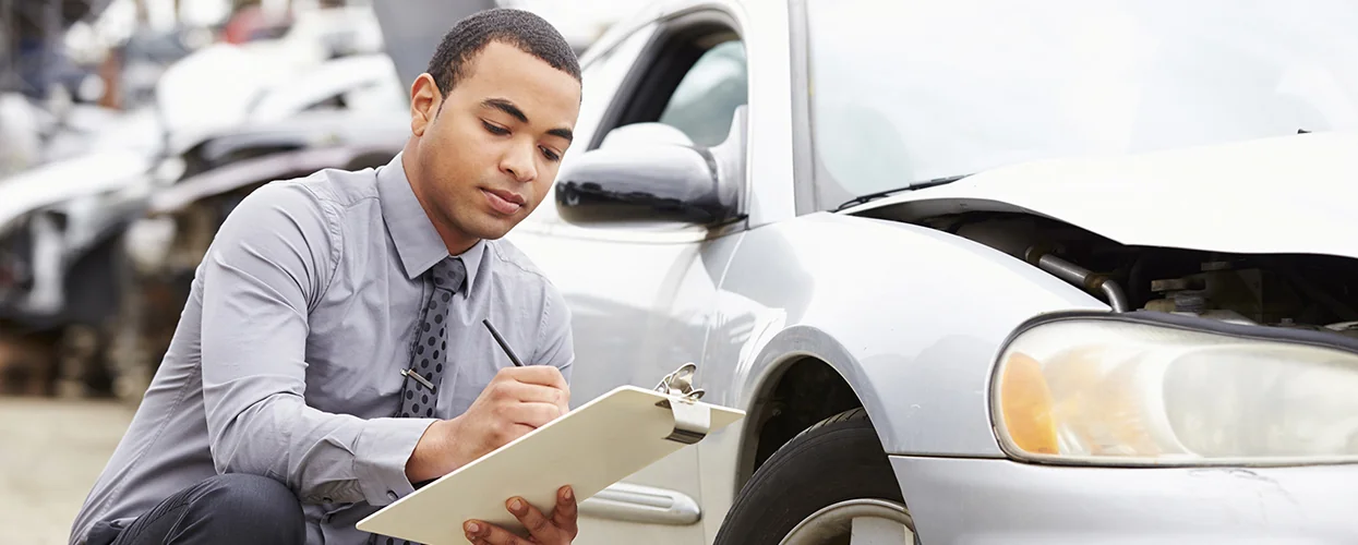 A collision service tech going over a daamged car