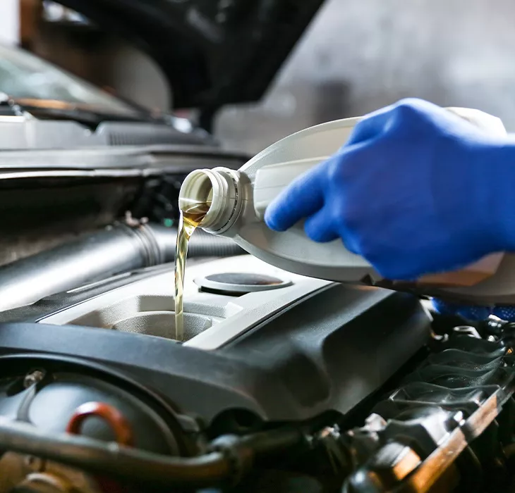 Service mechanic pouring oil into a car