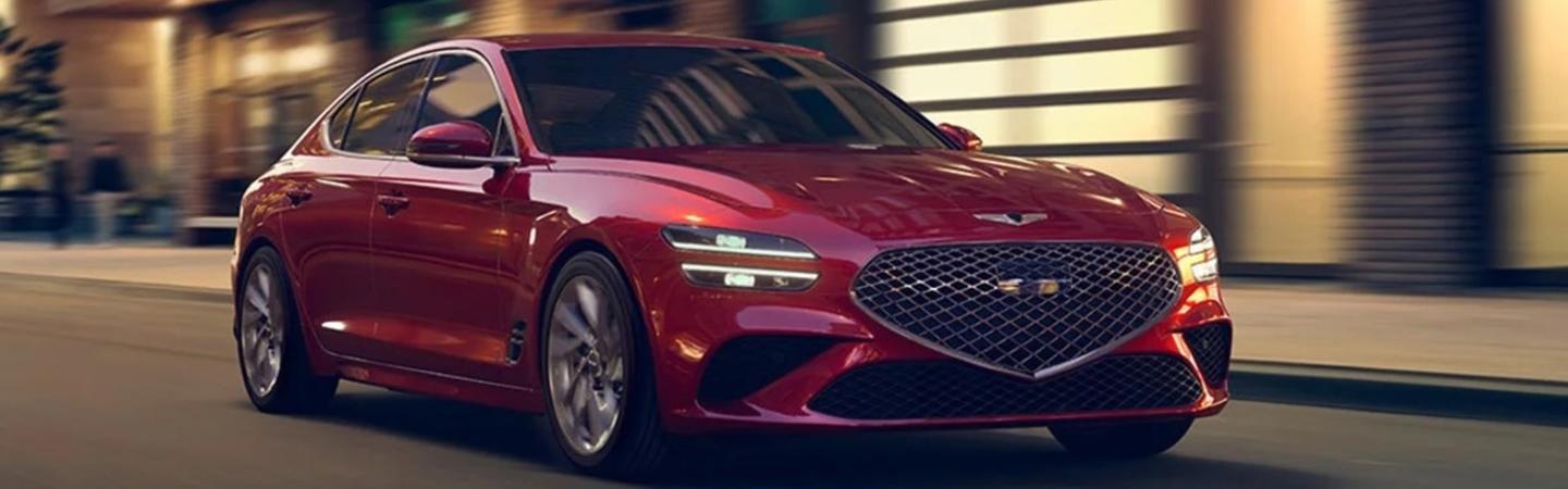 Red 2022 Genesis G70 in motion driving in city at night