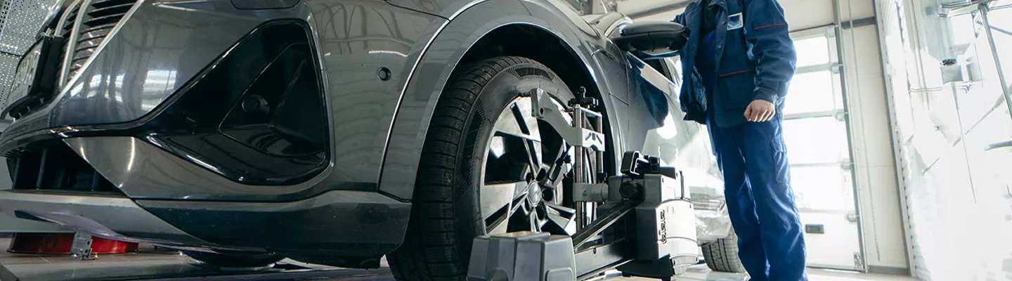 mechanic standing next to a vehicle doing a wheel alignment