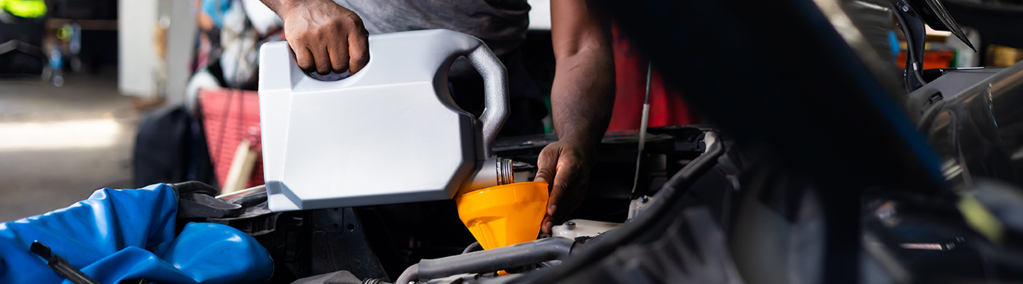 Service tech pouring oil into engine