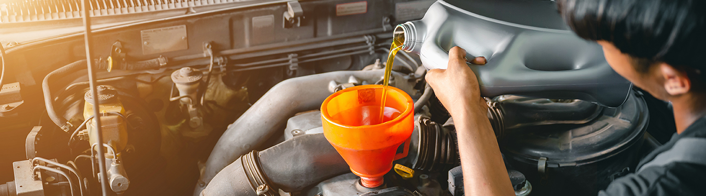 Technician pouring oil into an engine