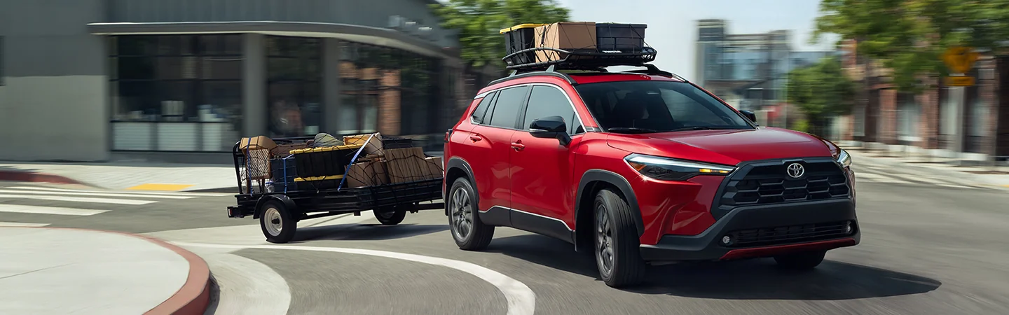 a red 2026 Toyota Corolla Cross L towing a moving trailer