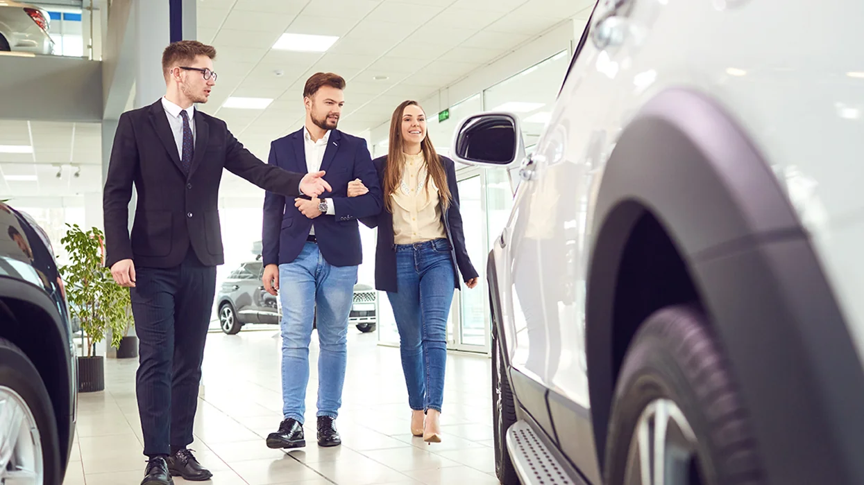 couple being shown a car in the showroom by car dealership representative