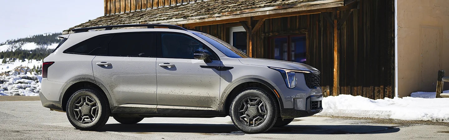 Side view of a 2025 Kia Sorento parked next to awood cabin