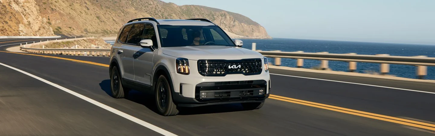 Front view of a gray 2025 Kia Telluride Driving on an ocean side road