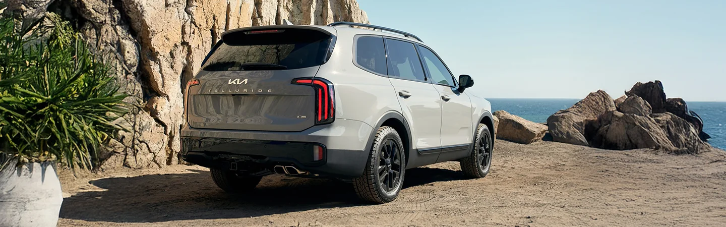 Back side view of a gray 2025 Kia Telluride by some rocks overlooking the ocean