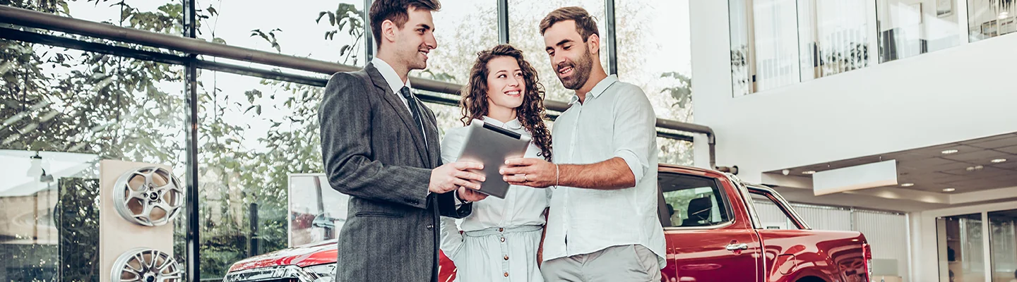 couple speaking with car salesman in showroom