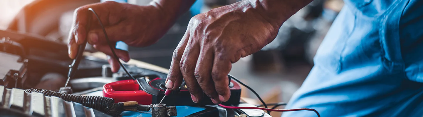 auto mechanic working testing power on circuit with meter
