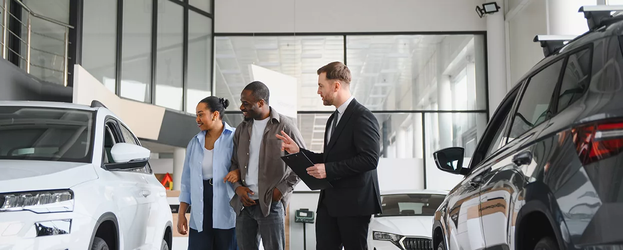 Car salesman showing a couple a new vehicle