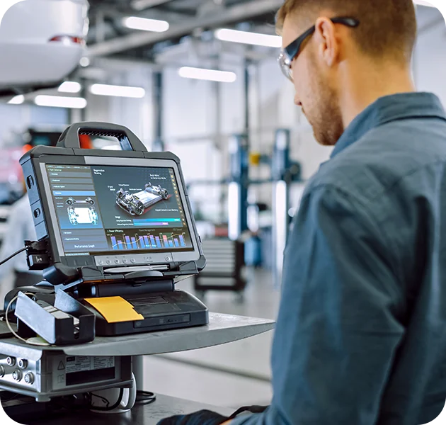 mechanic in the shop room running a diagnosis of a vehicle on the computer