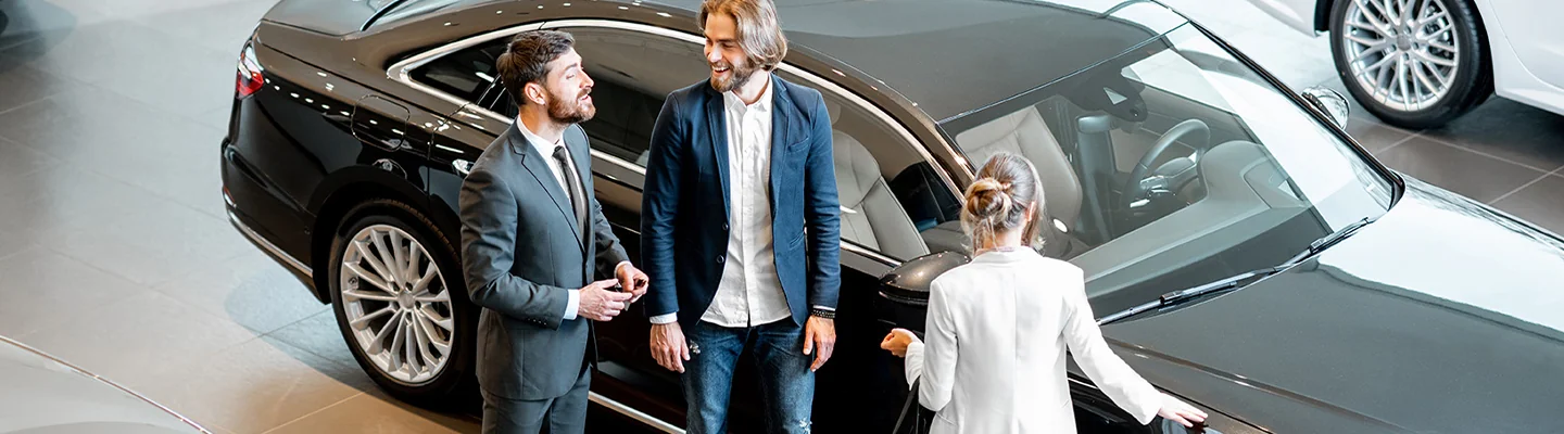 a couple looks over a vehicle while discussing financing with salesperson in showroom