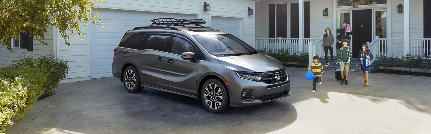 a silver 2026 Honda Odyssey EX-L with a roof rack on top parked in front of home