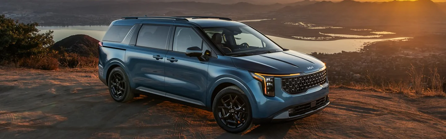 Side view of a parked 2025 Kia Carnival with a lake in the background