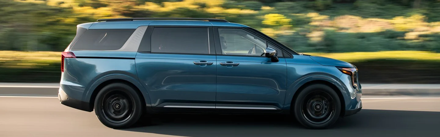 Side view of a 2025 Kia Carnival driving on a road