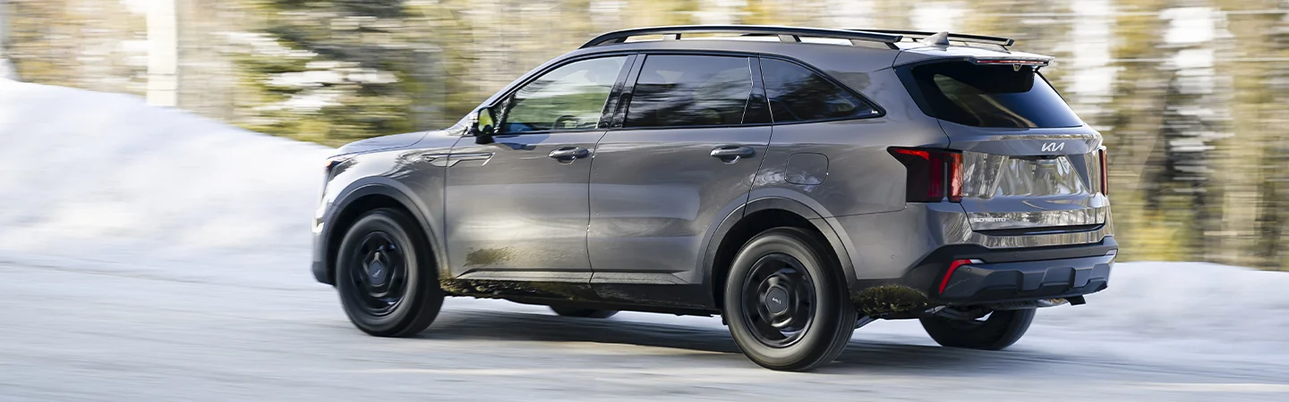 Side view of a gray 2025 Kia Sorento driving in some snow