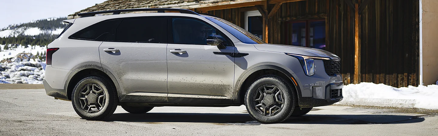 Side view of a parked gray 2025 Kia Sorento at a store  in the snow