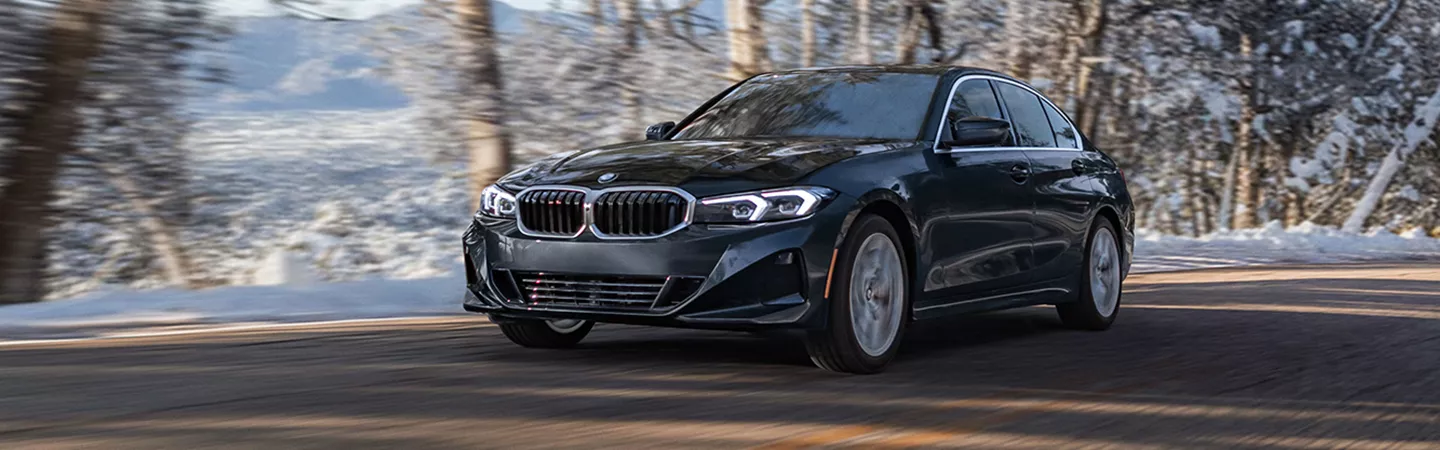 BMW 3 Series driving thorugh a forest with snow on the trees