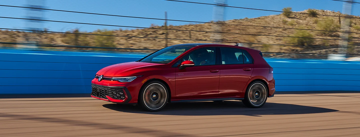 Side view of a red 2025 Volkswagen Golf GTI drving on a track