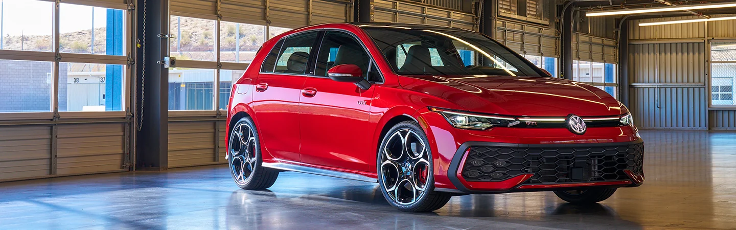 Front sdie view of a red 2025 Volkswagen Golf GTI parked in a garage