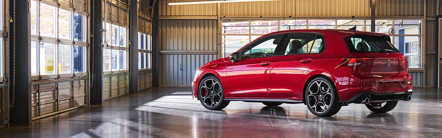 Back side view of a red 2025 Volkswagen Golf GTI parked in a garage