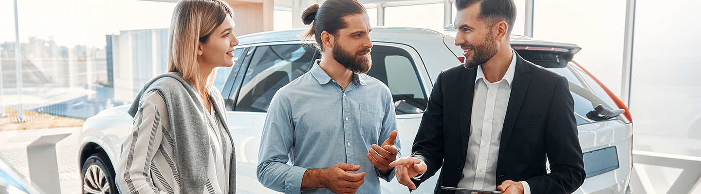Couple in the market for a vehicle speaking with a salesman.