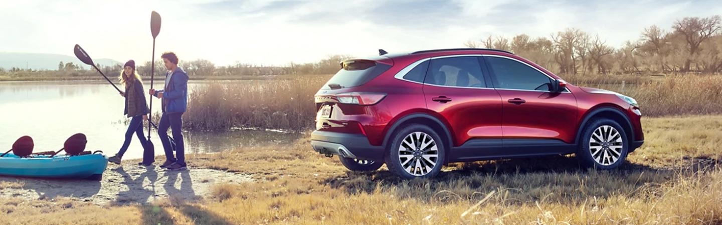 A red 2021 Ford Escape parked next to a couple going kayaking 