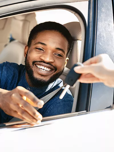 Person inside their car being handed a set of keys