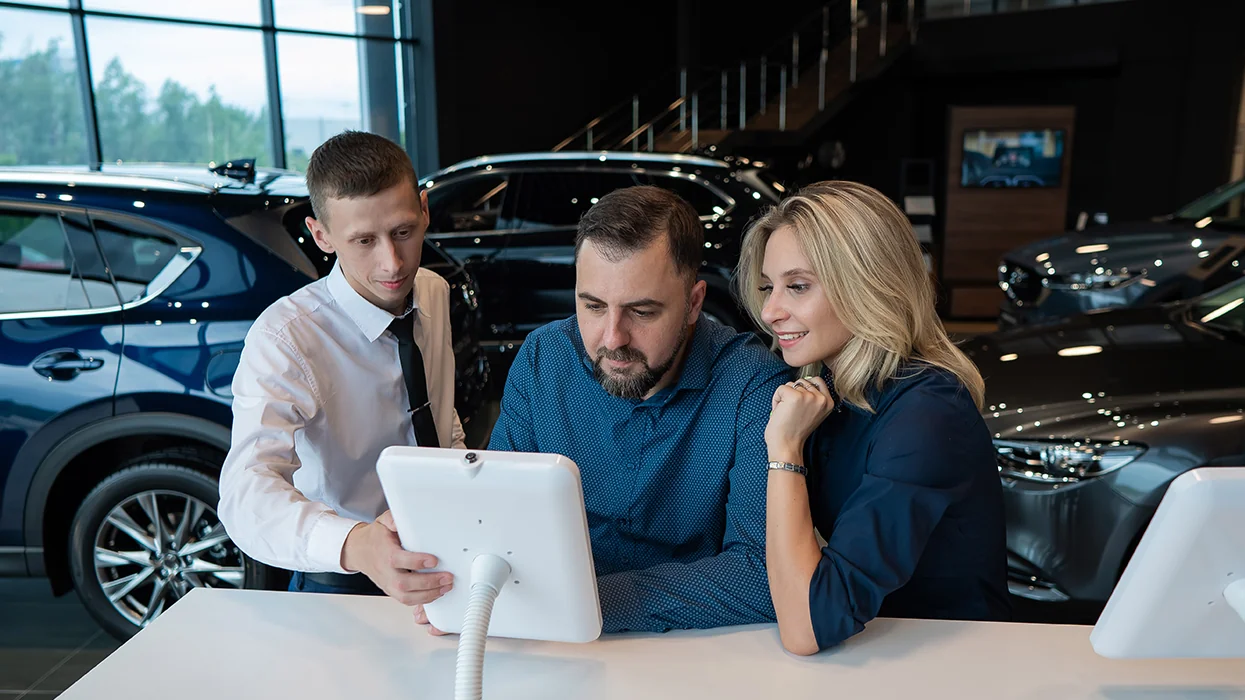 couple speaking with car salesman in showroom