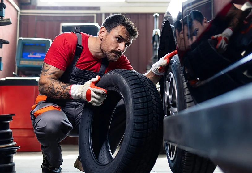 auto mechanic installing tires on car in service bay