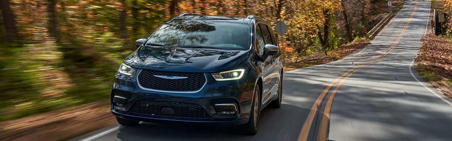 2026 Chrysler Pacifica driving on a wooded road in autumn