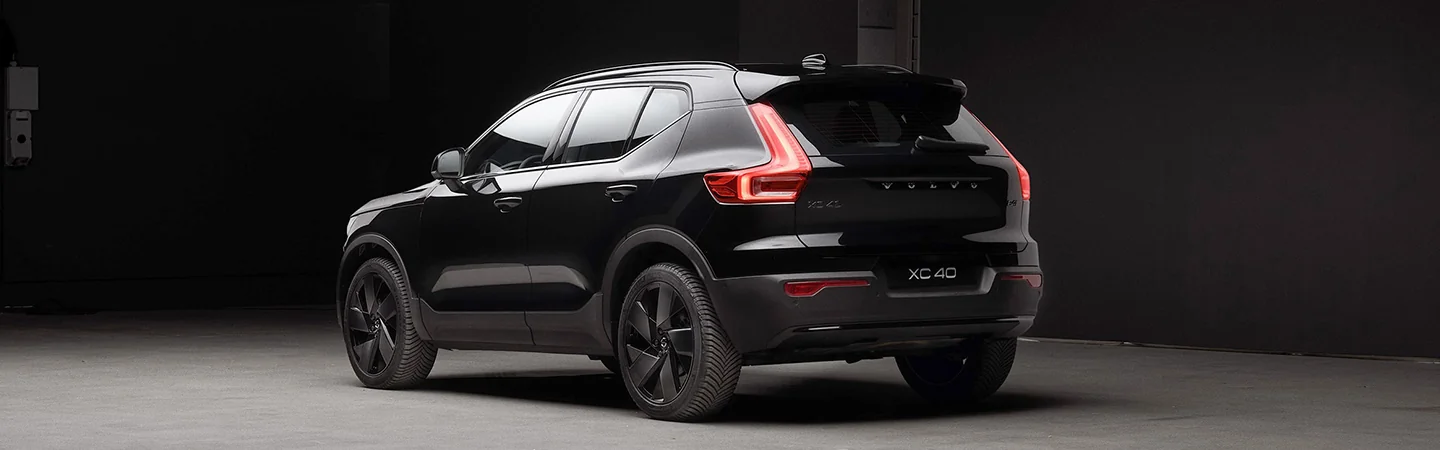 Rear side view of a 2026 Volvo XC40 parked in a darkly lit parking garage