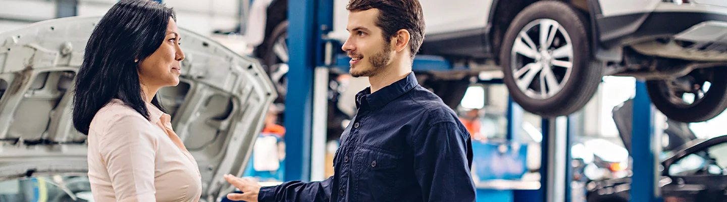 car repair tech speaking with another person in service bay