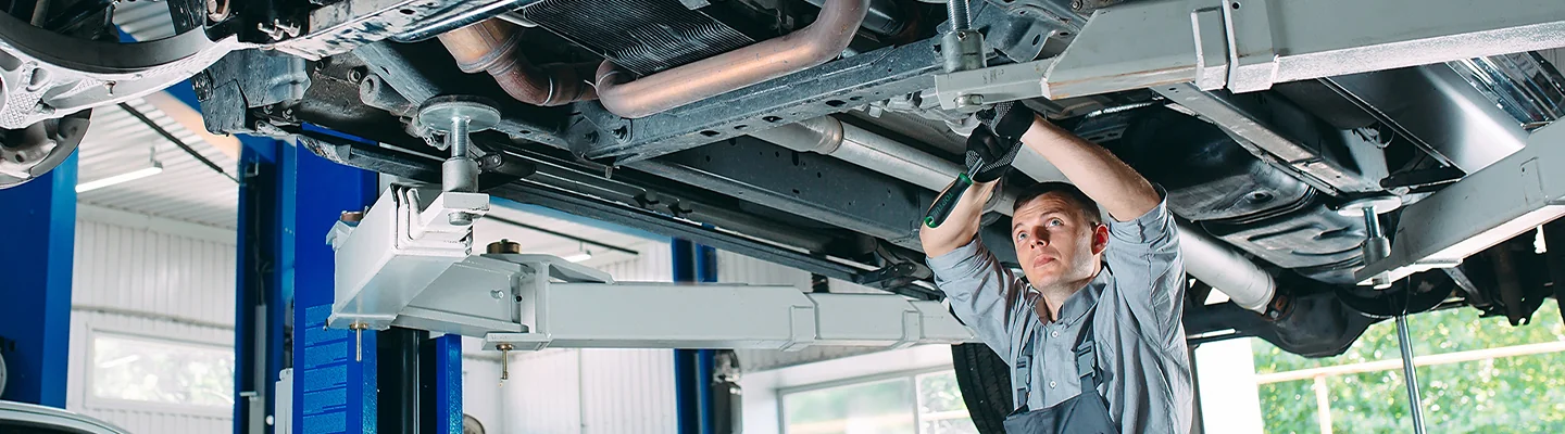 auto mechanic working under car on a lift