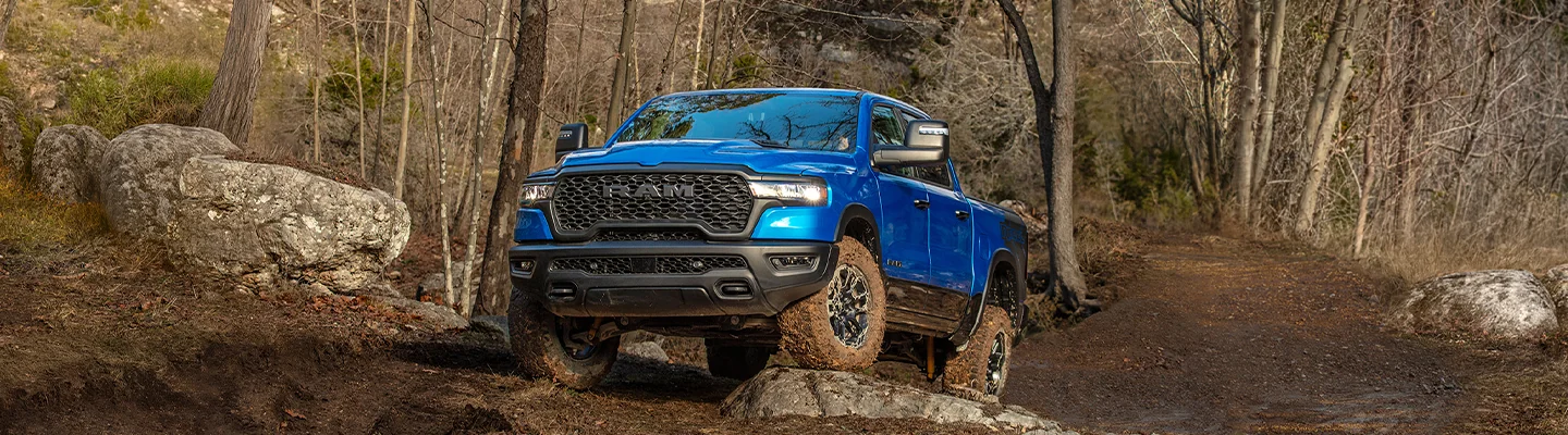 a blue RAM 1500 climbing some rocks