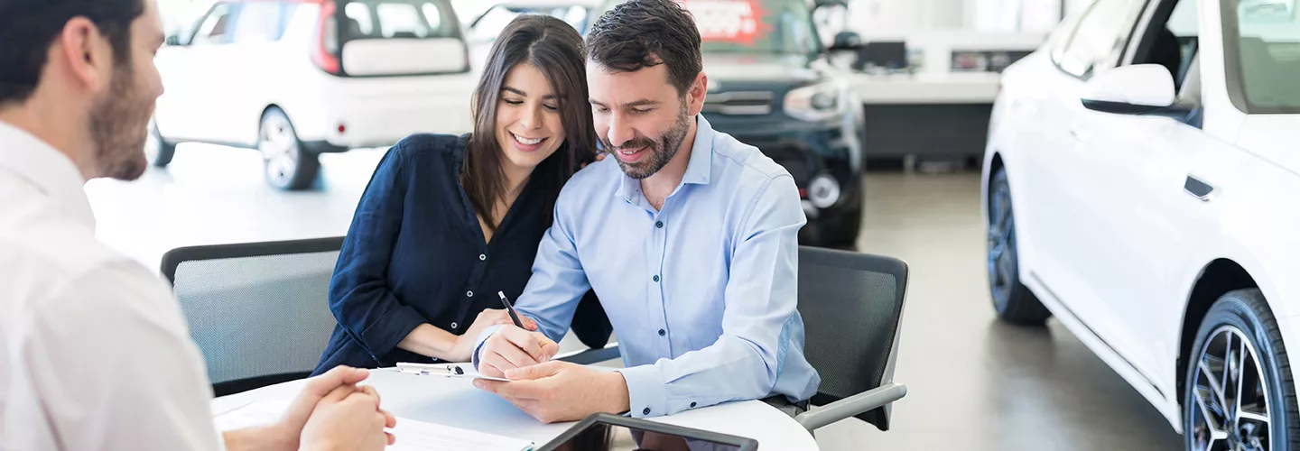 Couple signign a document in a car dealership