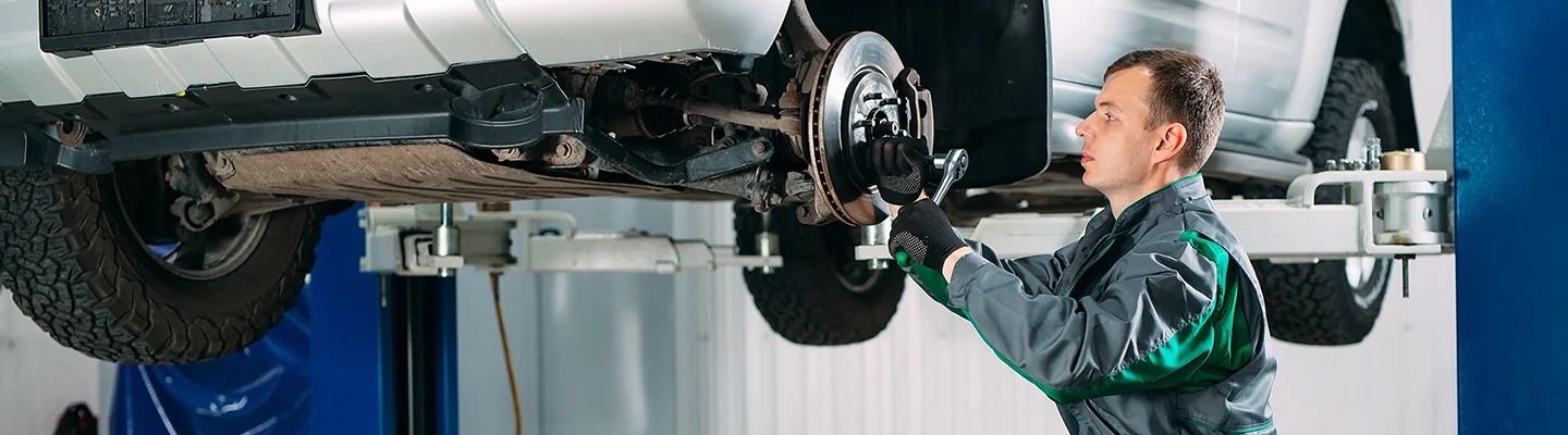 auto mechanic working on brake on a car on a lift