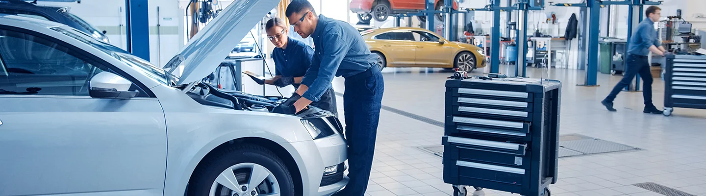 Two service techs working on a car egine